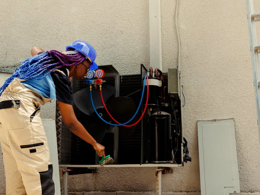 Freshwind AC Service technician repairing an AC unit with a gas pressure gauge in Greater Noida