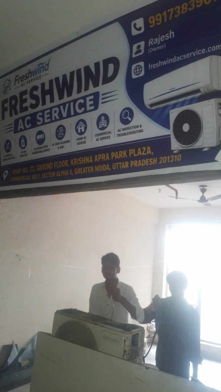 Freshwind AC Service technician checking gas pressure on an AC unit at the shop