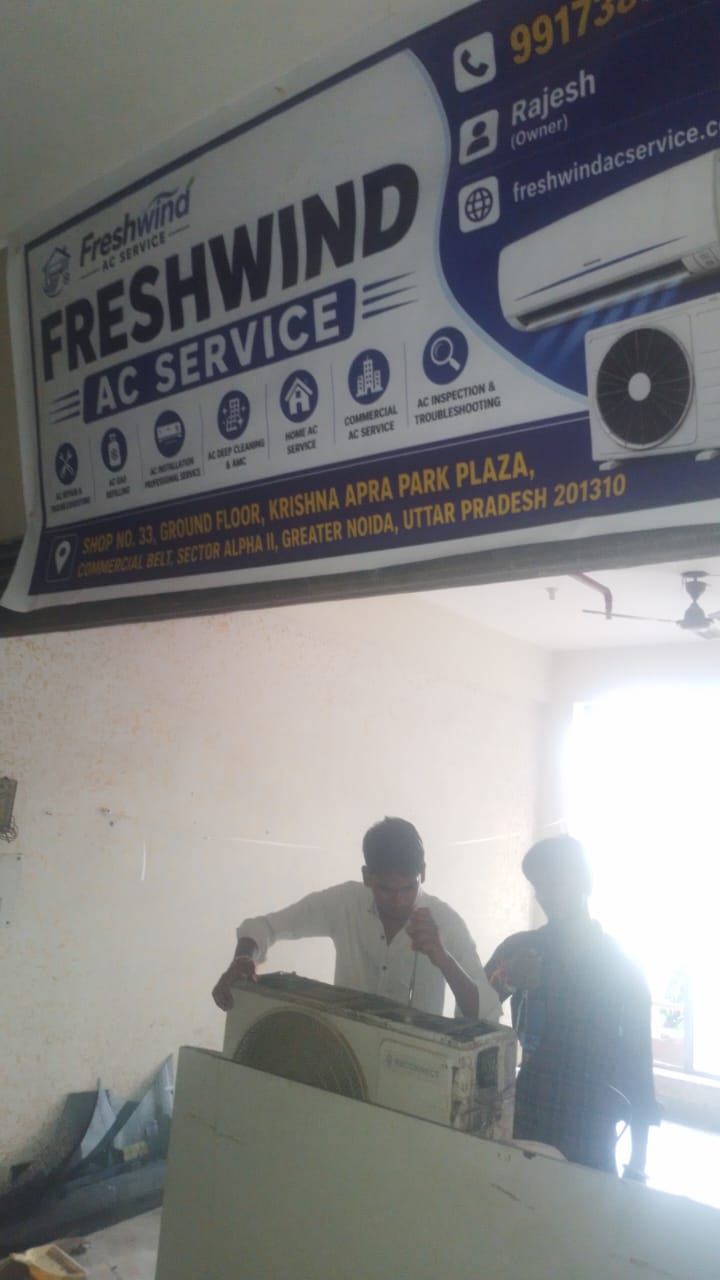 Freshwind AC Service technicians working on an AC unit at the shop counter